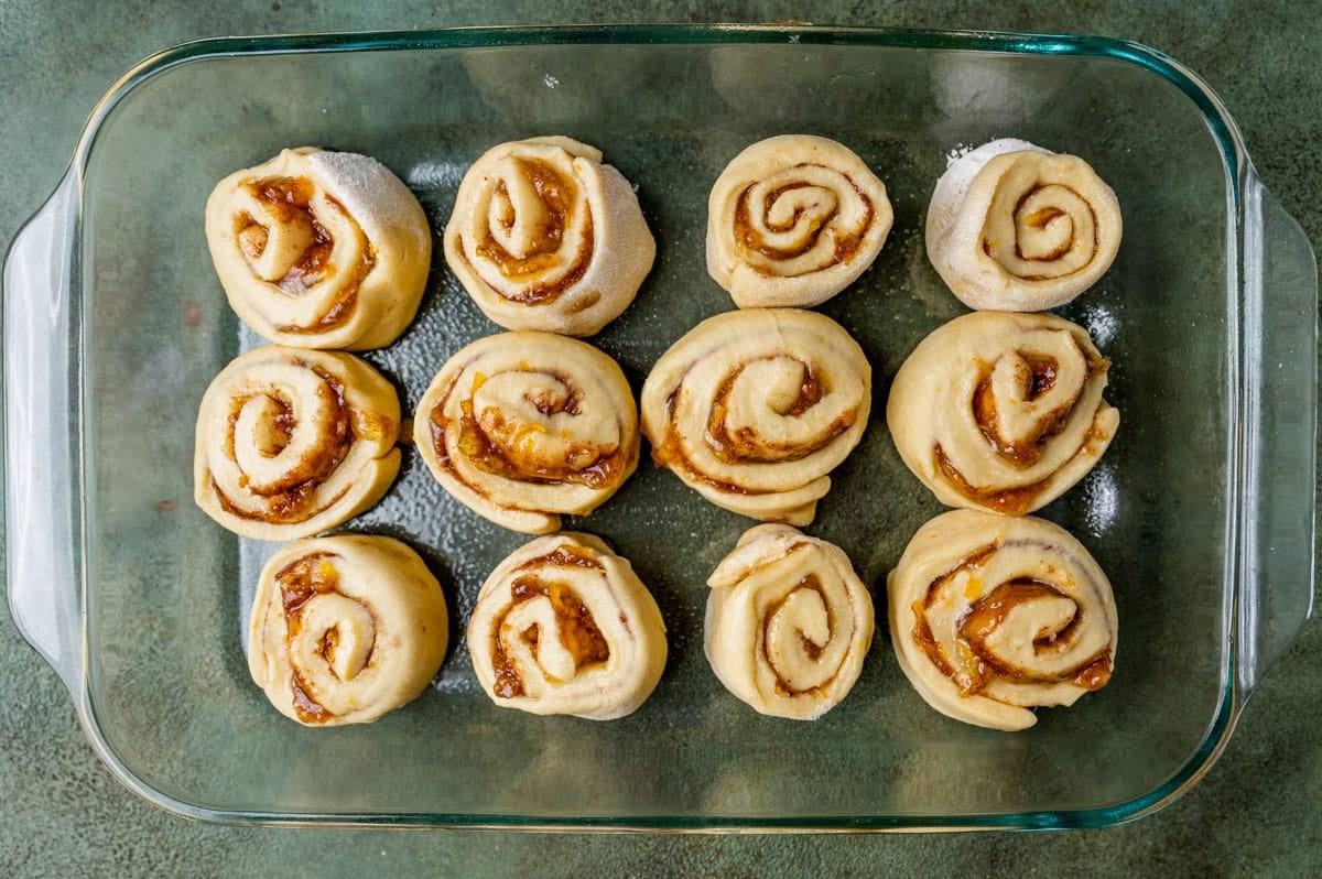 unbaked orange rolls in a glass 9x13 pan