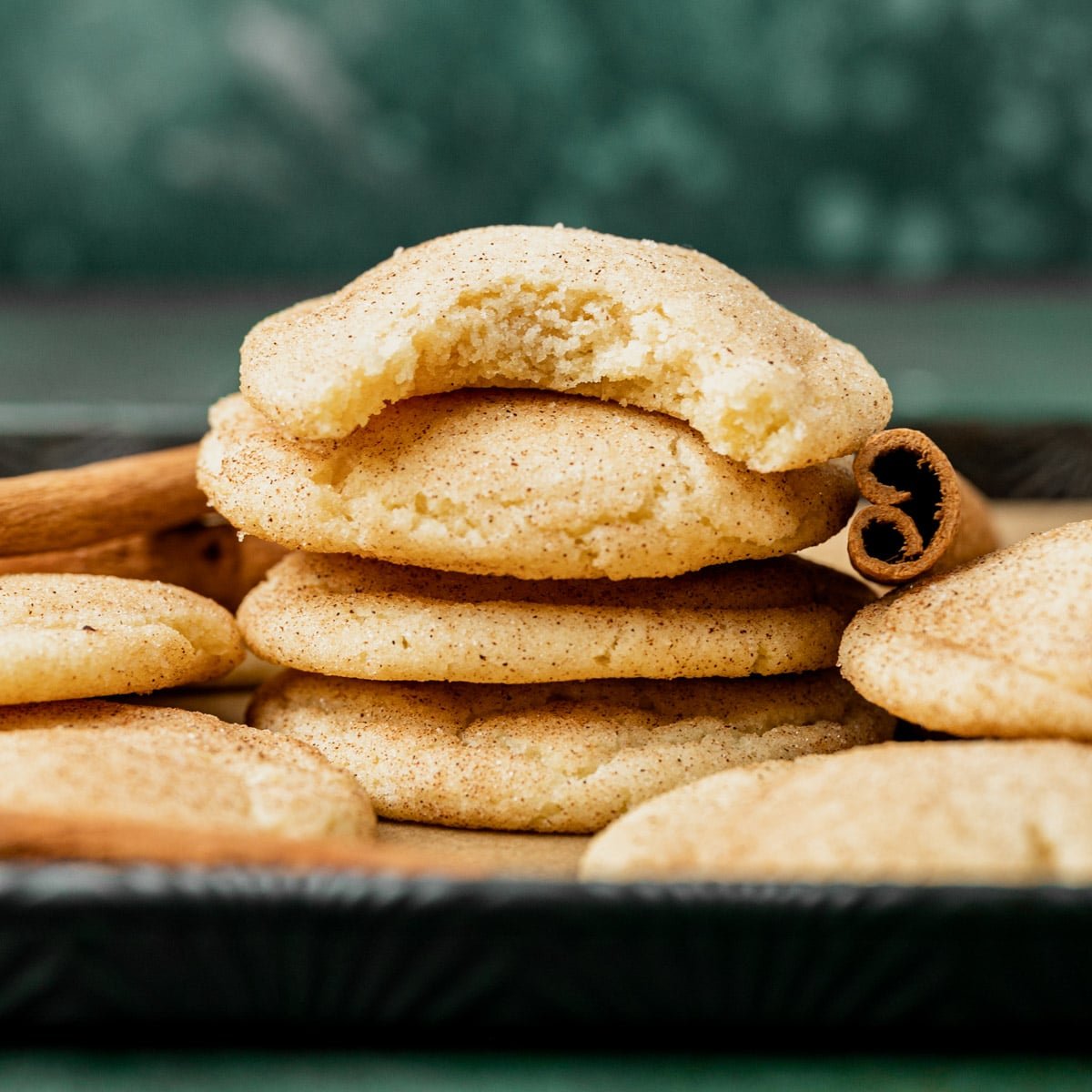 a stack of snickerdoodle cookies, one with a bite out of it