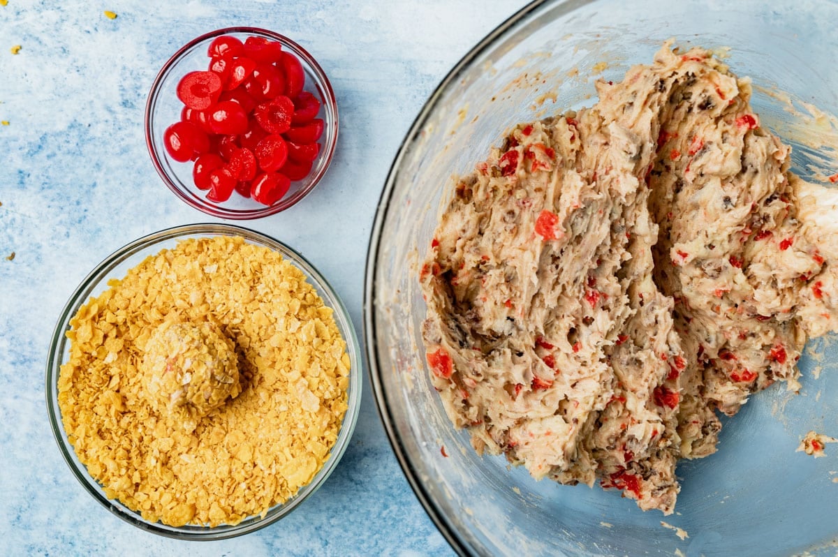 cookie dough, cornflakes and cherries in bowls on a table