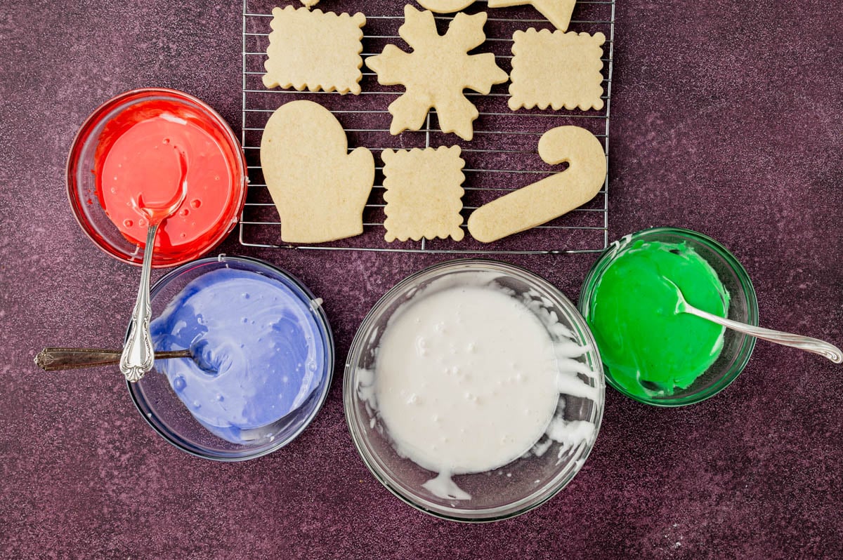 overhead view of colored sugar cookie icing and cut out cookies