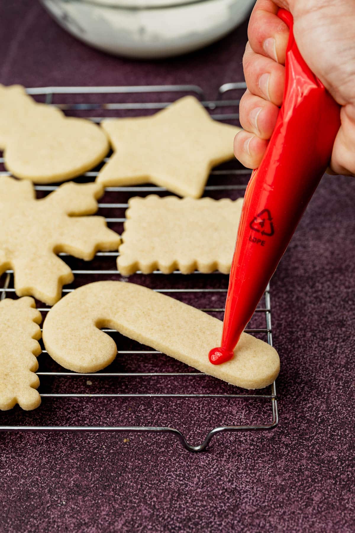 piping sugar cookie icing on a candy cane cookie