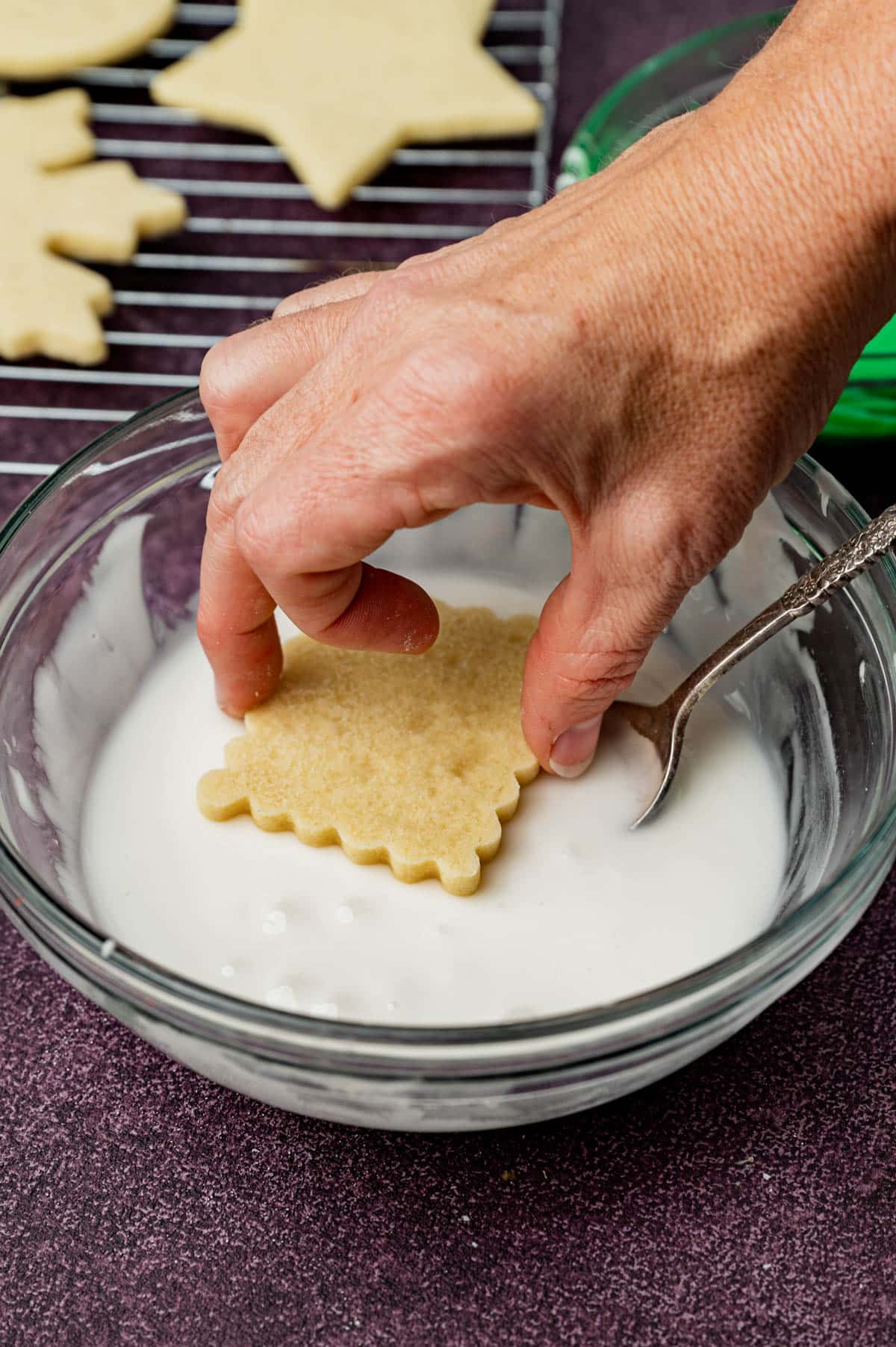 dipping a sugar cookie in powdered sugar frosting