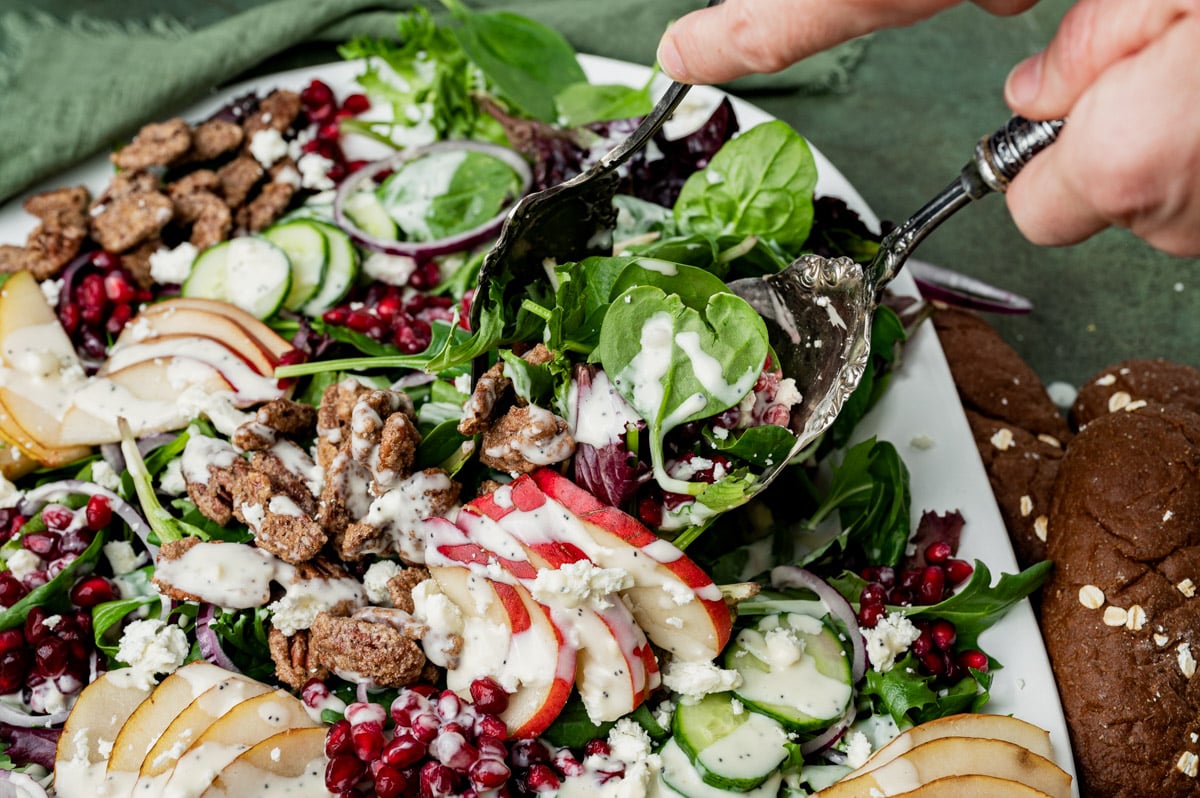 salad tongs tossing pear salad with candied pecans