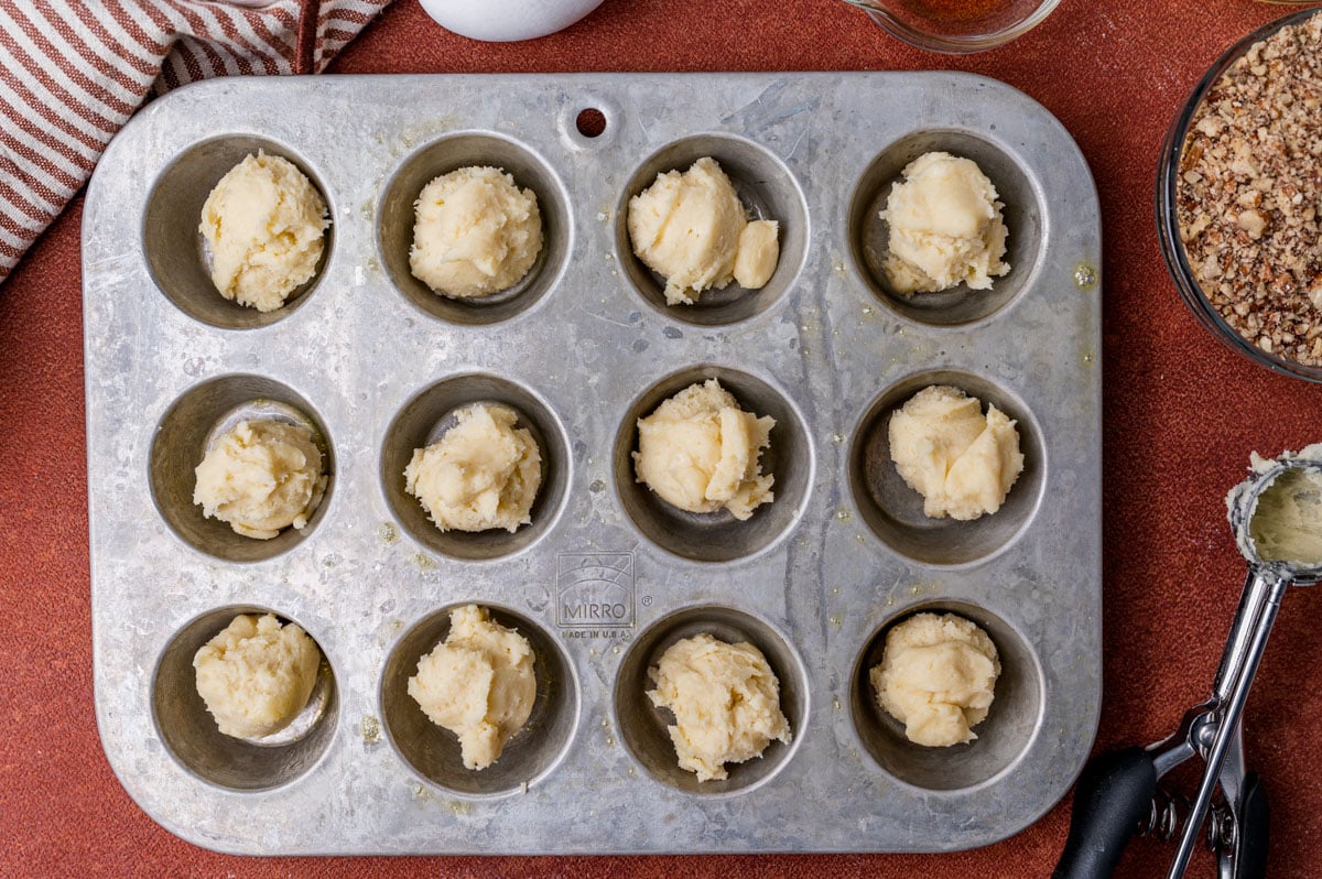 a mini muffin pan with dough balls in it