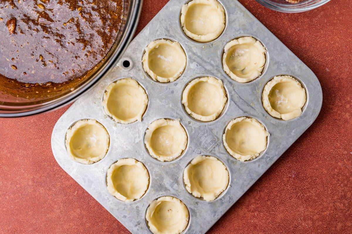 crusts in a mini muffin pan for pecan tarts