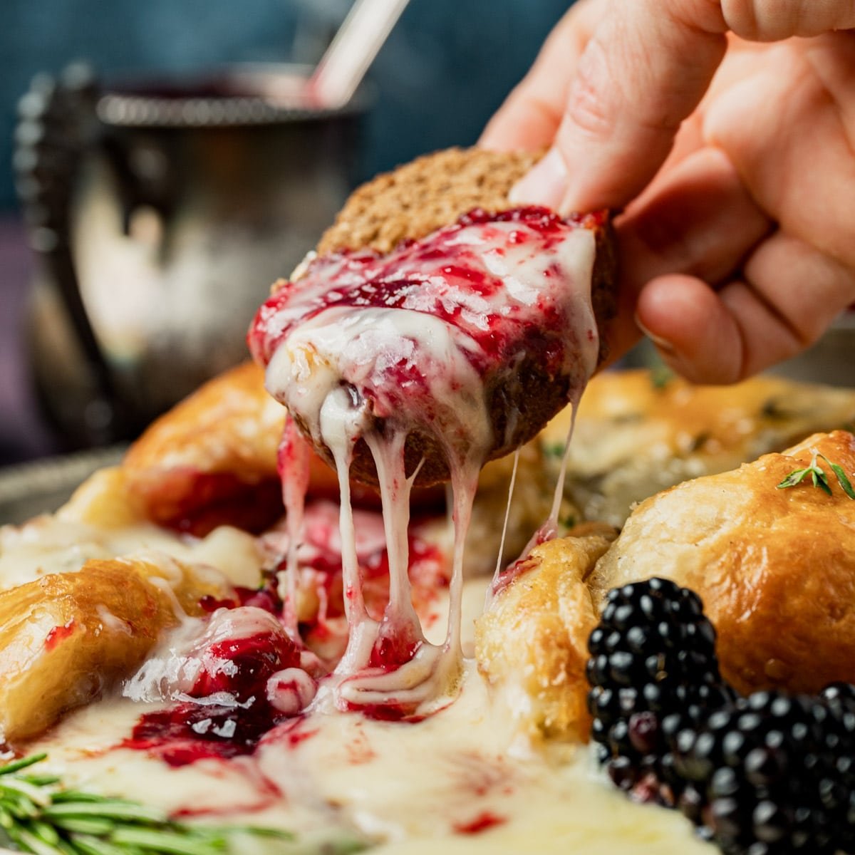 a piece of bread with melted brie and blackberry jam