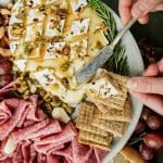 a knife putting baked brie on a cracker