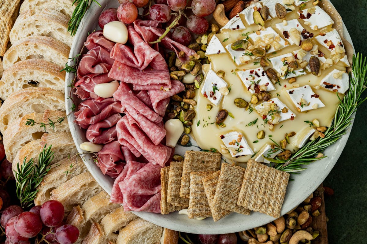 a plate of baked brie, meats and nuts