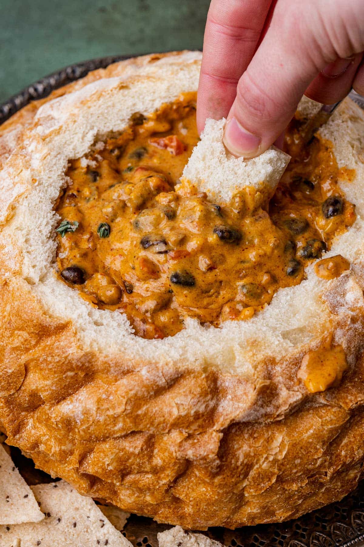 dipping a piece of bread in cheesy bean dip