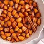 fried apples with cinnamon sticks in a skillet