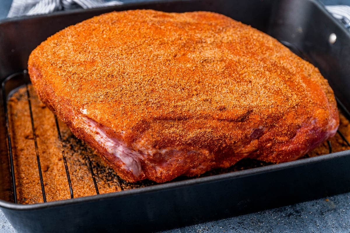 uncooked pork shoulder with spice rub all over the outside