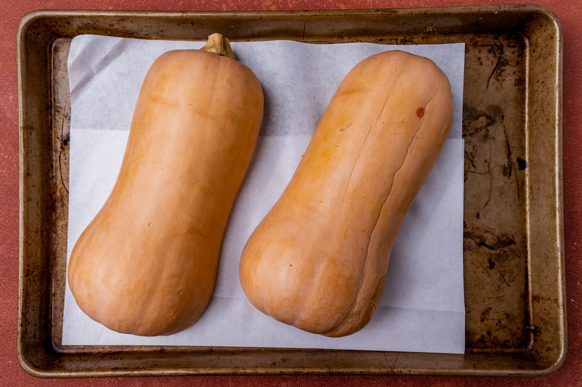 butternut squash cut in half on a baking sheet