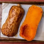 butternut squash cut in half on a baking sheet