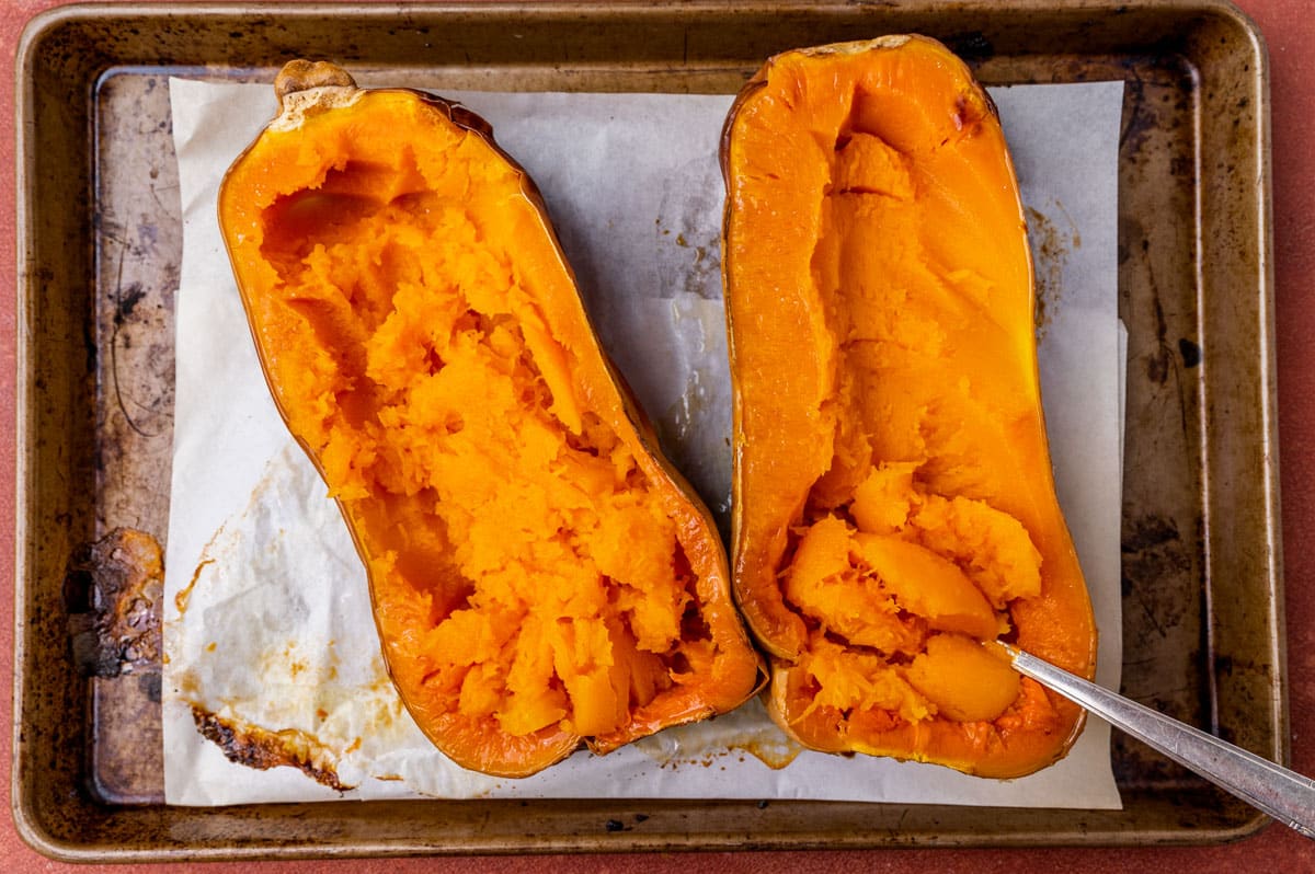 baked butternut squash on a pan with a spoon