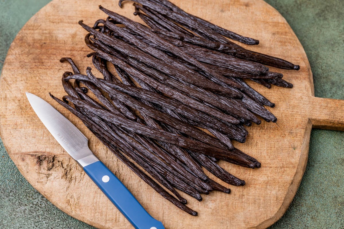 a cutting board with vanilla beans and a knife