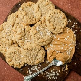 peanut butter oatmeal cookies on a cutting board with peanut butter and a spoon