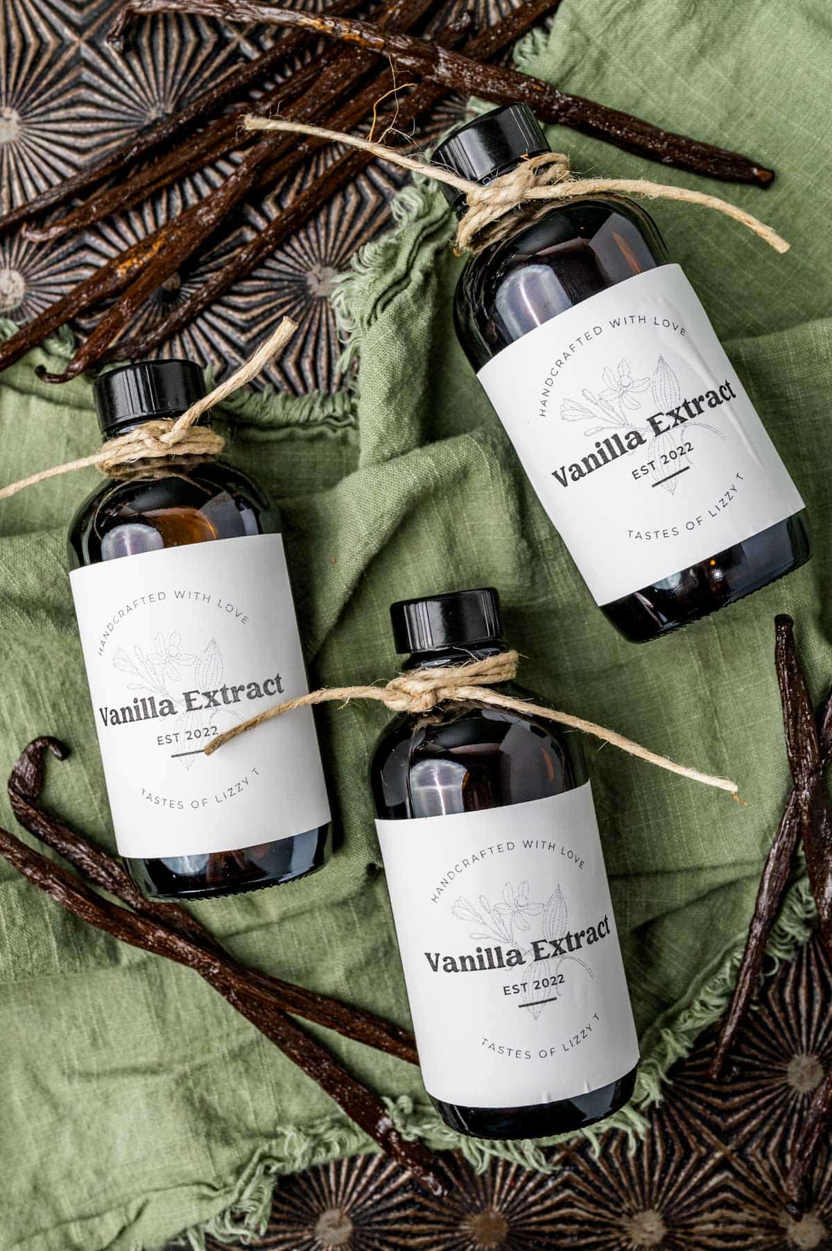 3 bottles of vanilla extract with vanilla beans on a table