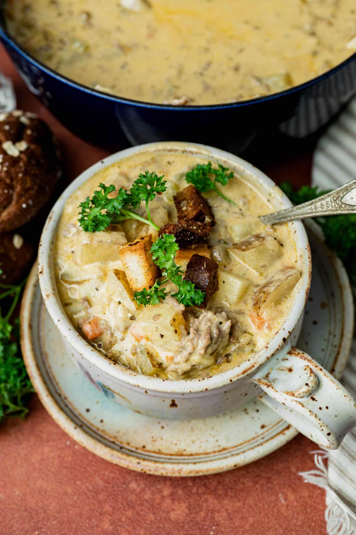 a bowl of cheeseburger soup with parsley and croutons