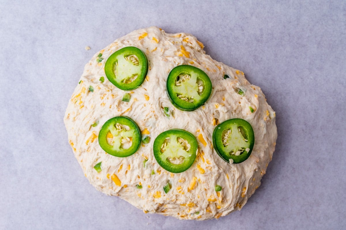 jalapeno slices placed over a bread dough ball
