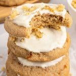 a stack of frosted carrot cookies, one with a bite out