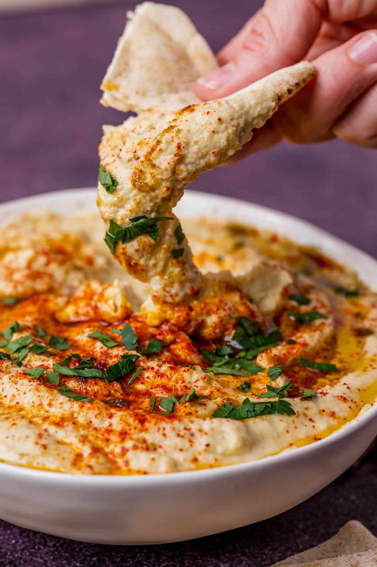 pita bread dipping into fresh hummus