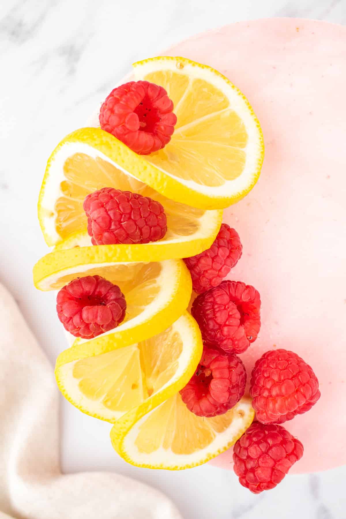 overhead view of a cake with lemon and raspberries on top