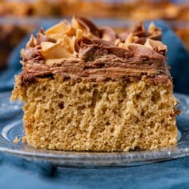 a piece of frosted peanut butter cake on a glass plate