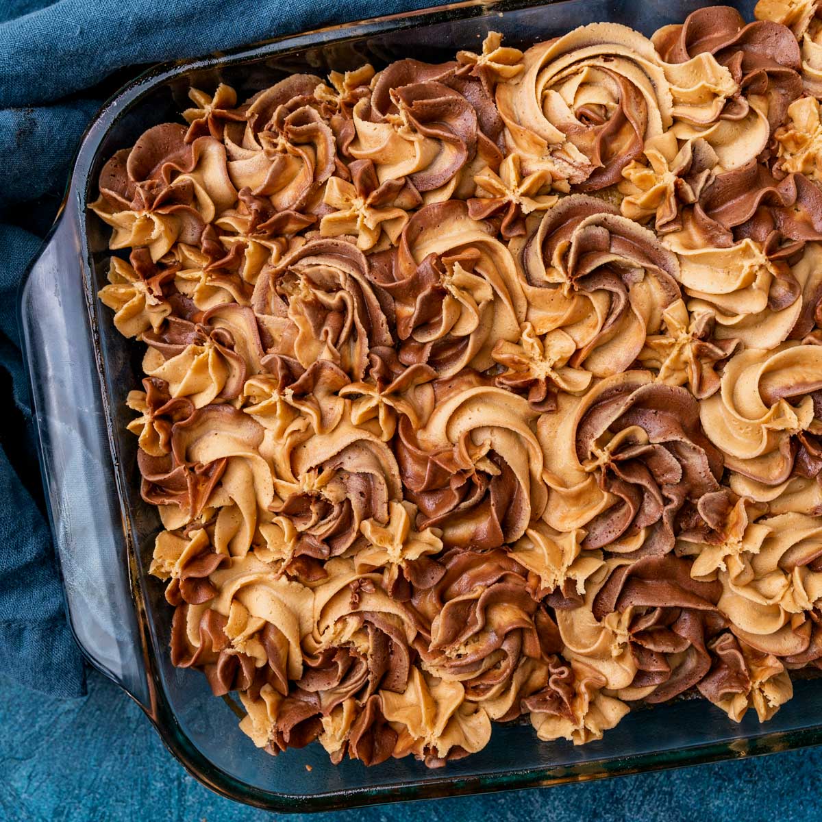 overhead view of a cake in a pan with swirls of peanut butter and chocolate frosting