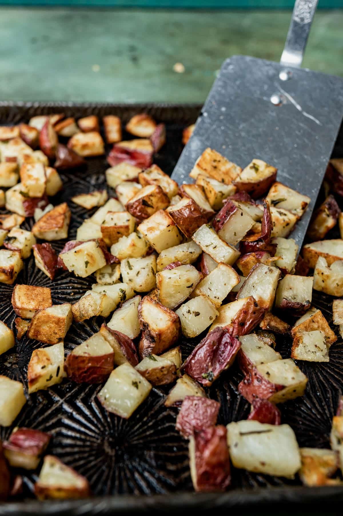 roasted red potatoes on a pan with a spatula