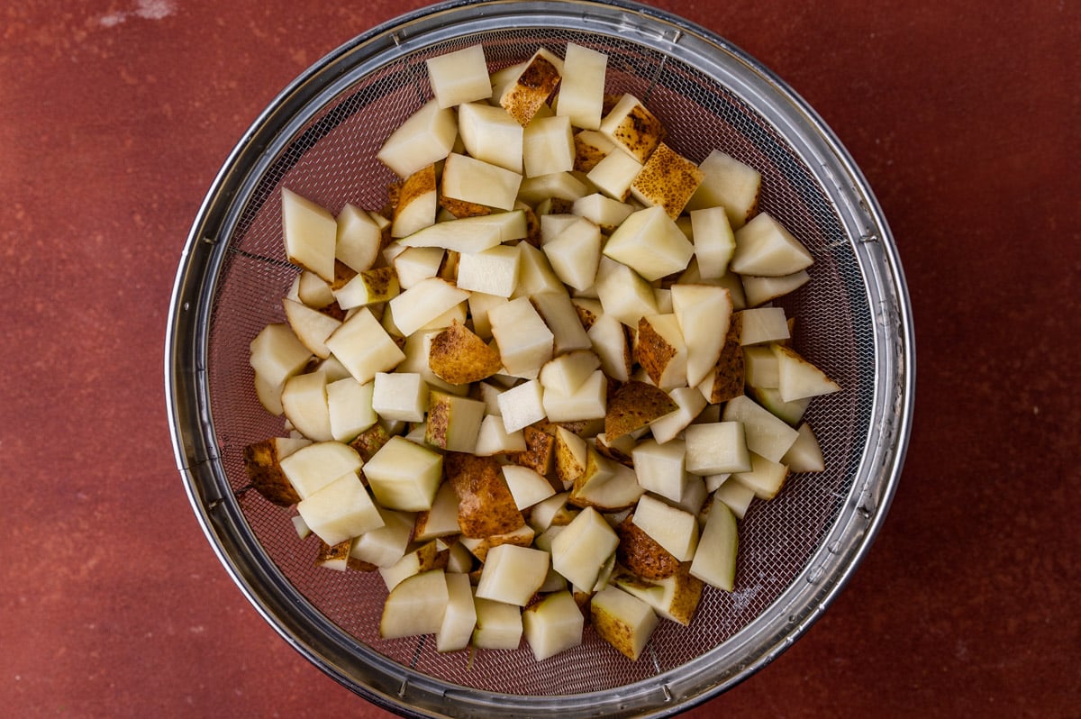 cubed potatoes in a strainer on a table