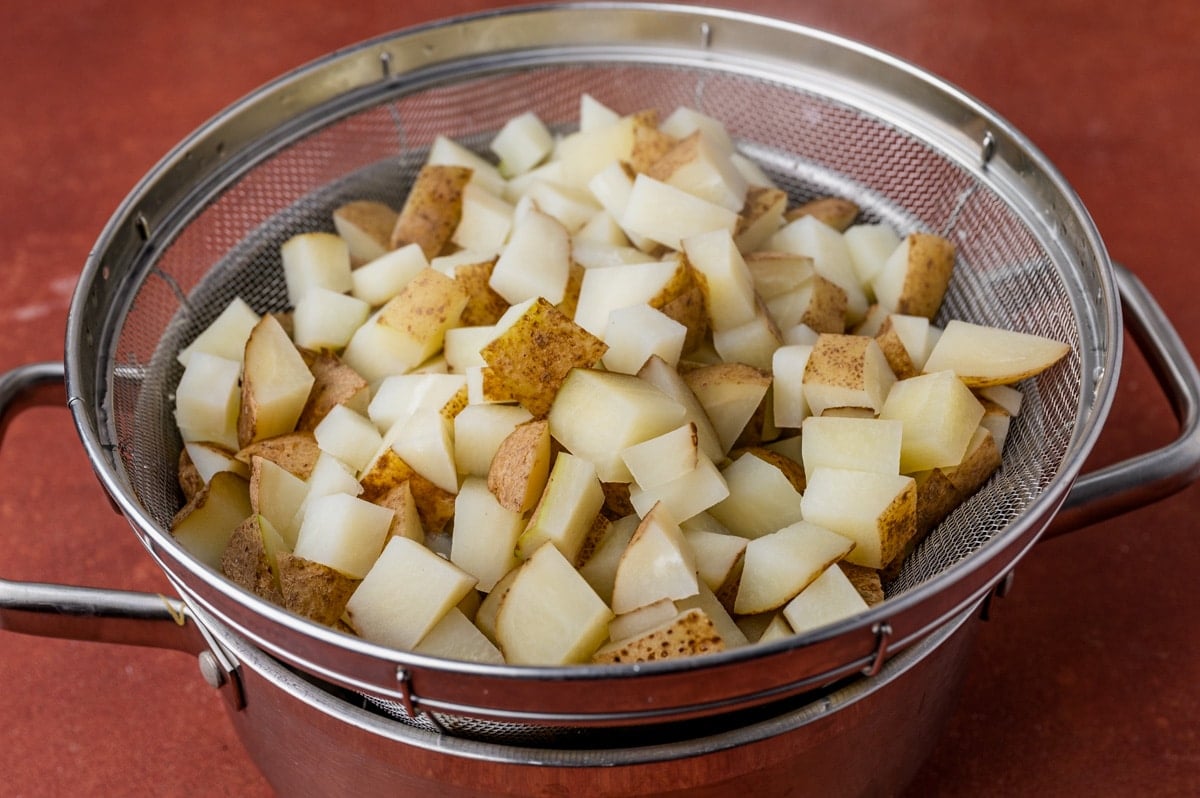 cooked potatoes draining in a strainer