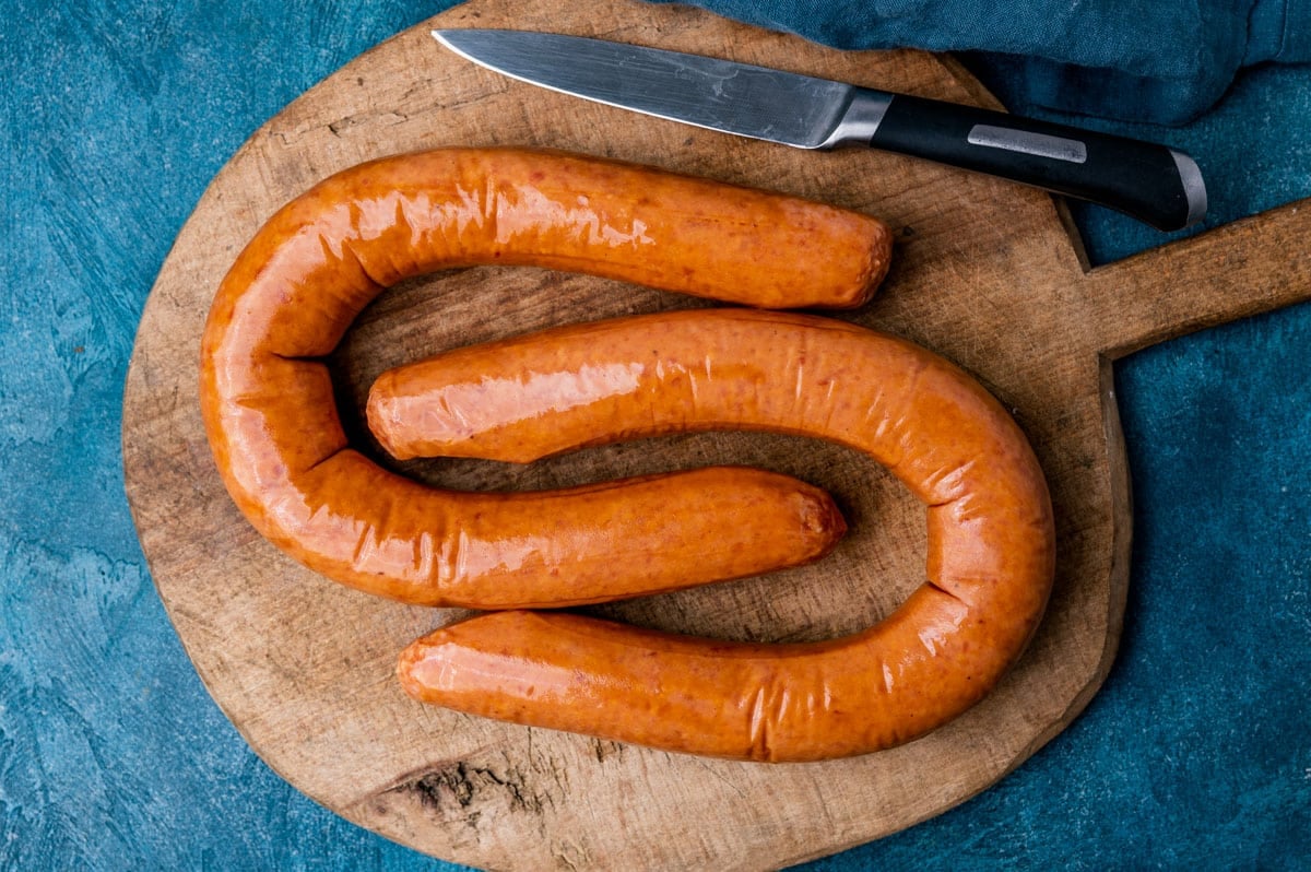 two links of kielbasa on a wooden cutting board