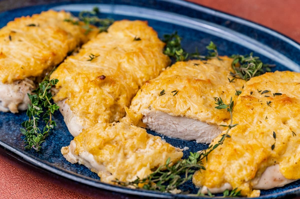 a mayo parmesan chicken breast cut in half on a blue plate