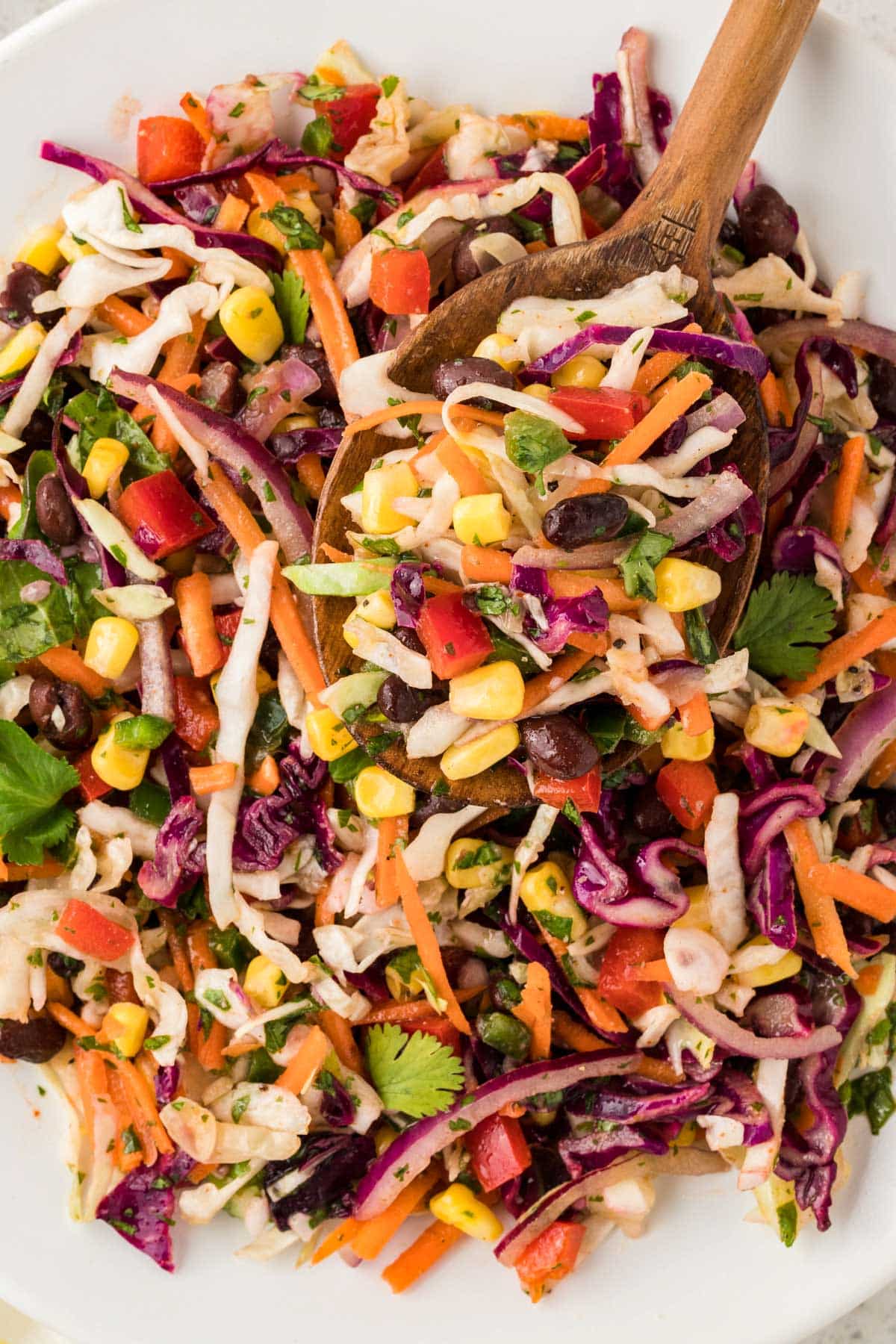 a bowl of mexican coleslaw salad with a wooden spoon