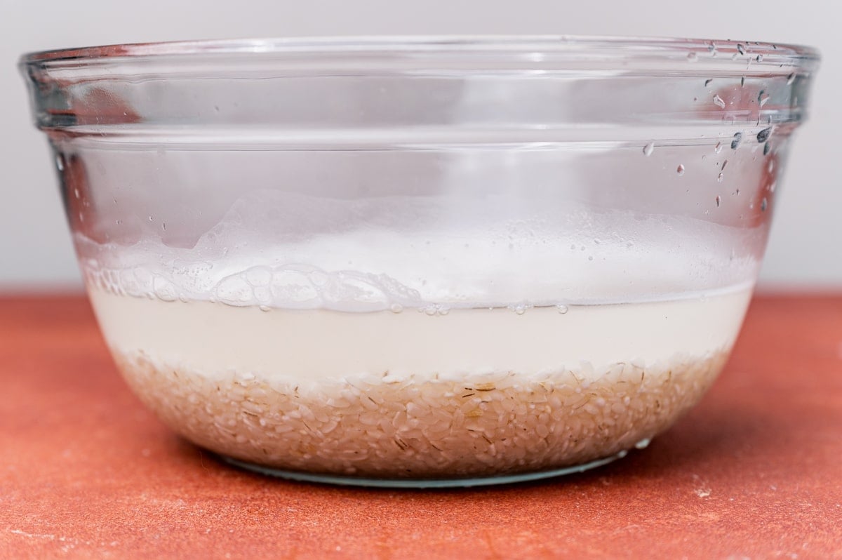 rice sitting in water in a glass bowl