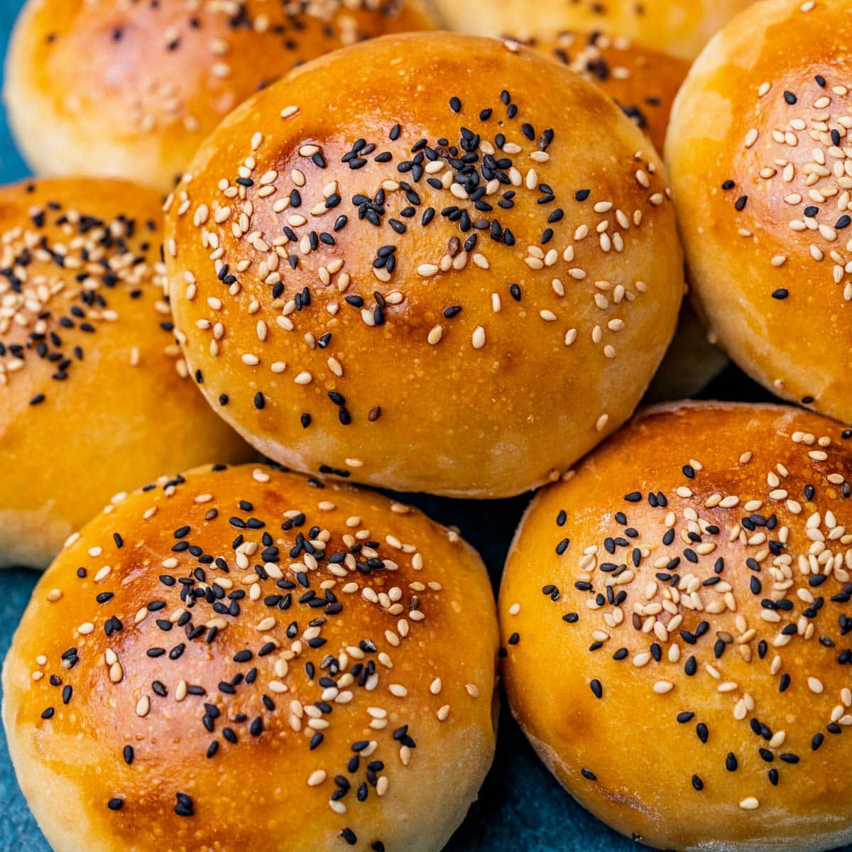 a pile of sesame seed sourdough buns