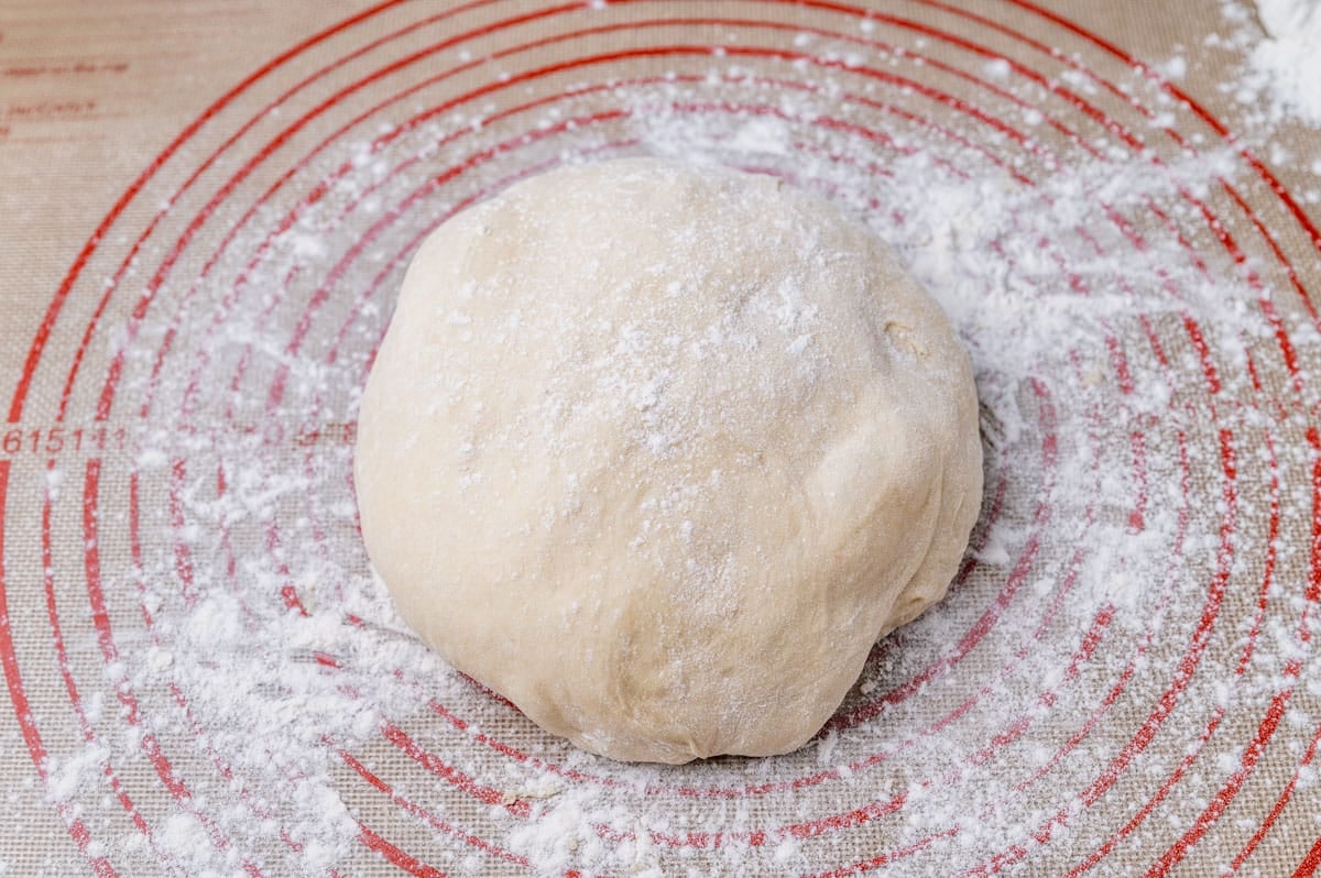 a dough ball sprinkled with flour on a pastry mat