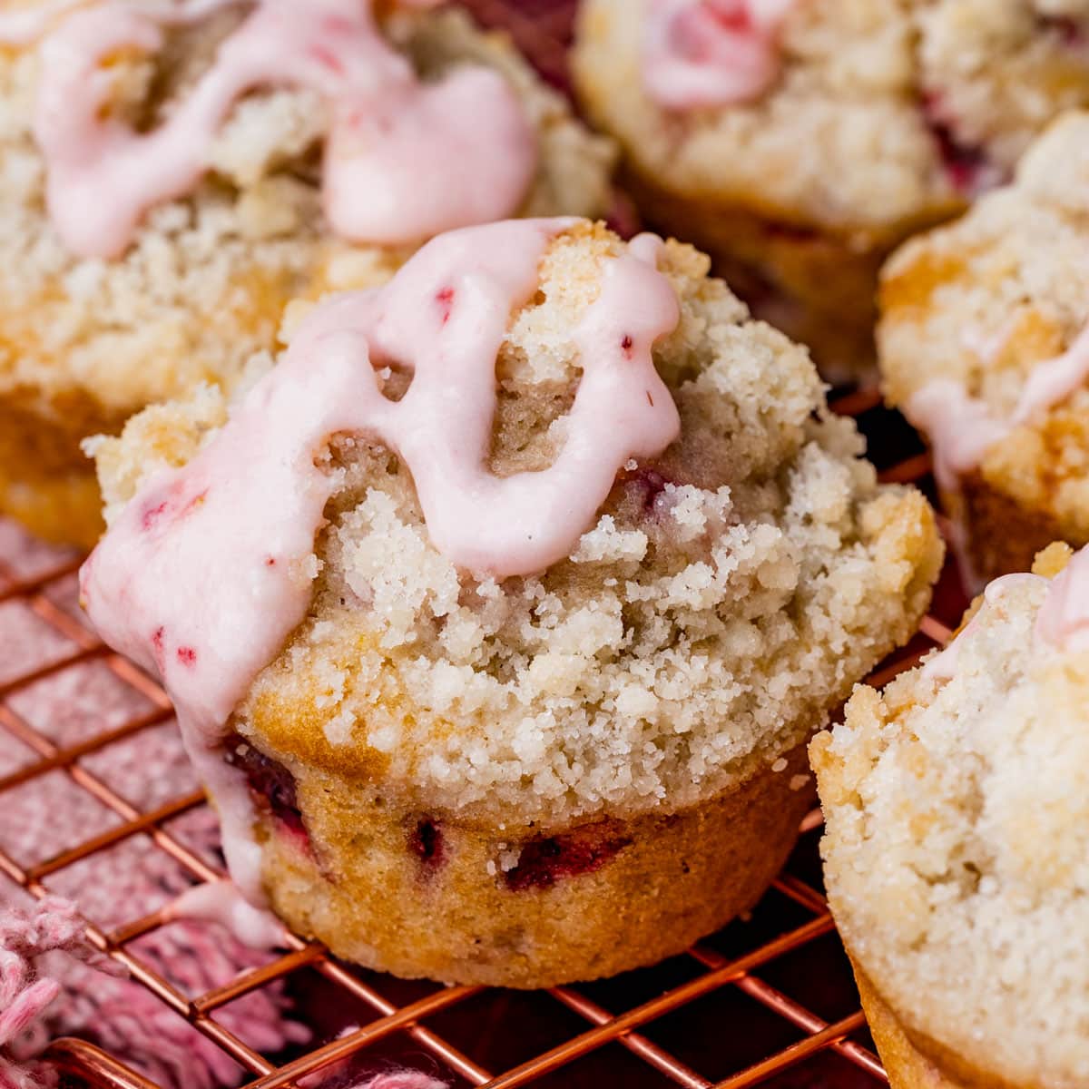 a strawberry muffin with crumb topping and glaze on a table