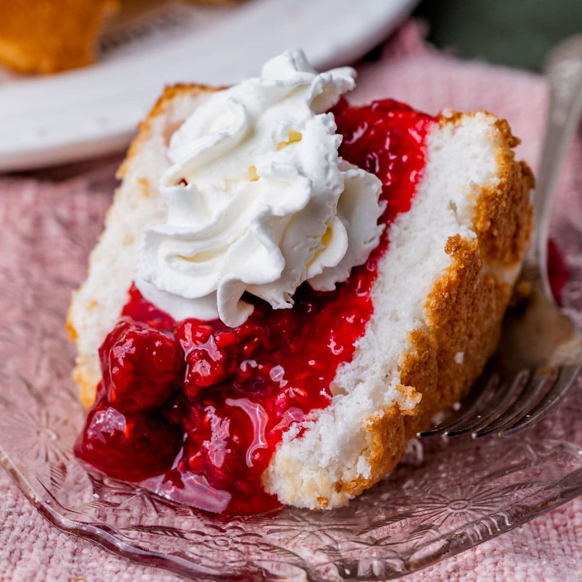 a piece of angel food cake on a plate with raspberry sauce and whipped cream