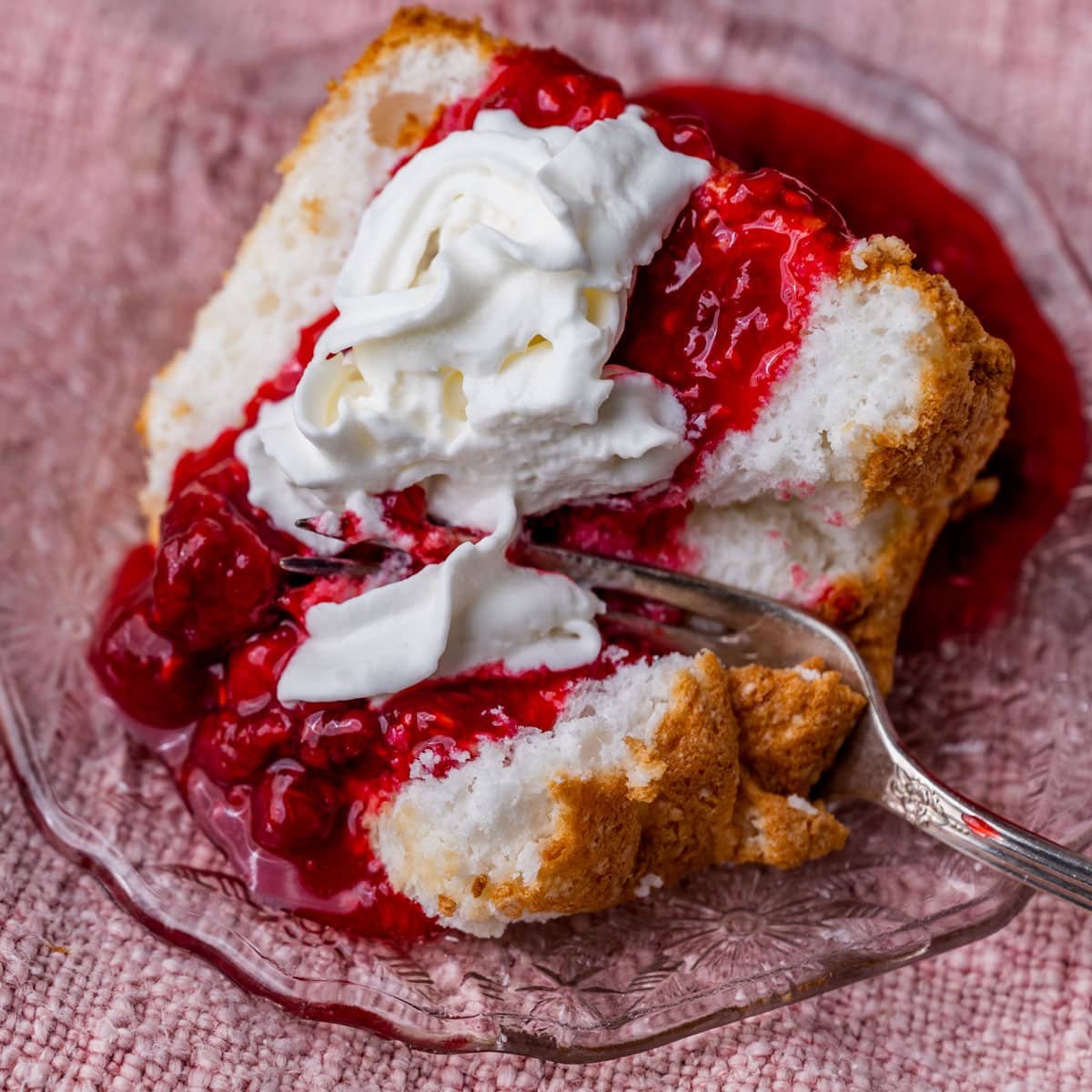 a piece of angel food cake on a plate with raspberry sauce and whipped cream