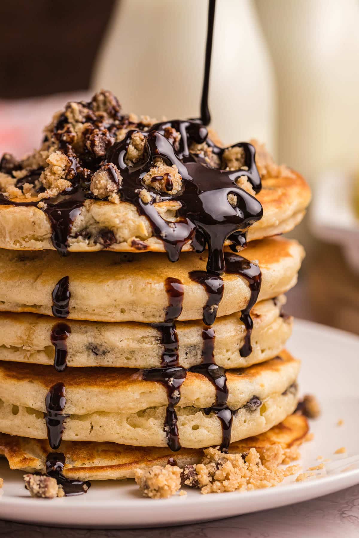 chocolate syrup pouring over chocolate chip pancakes