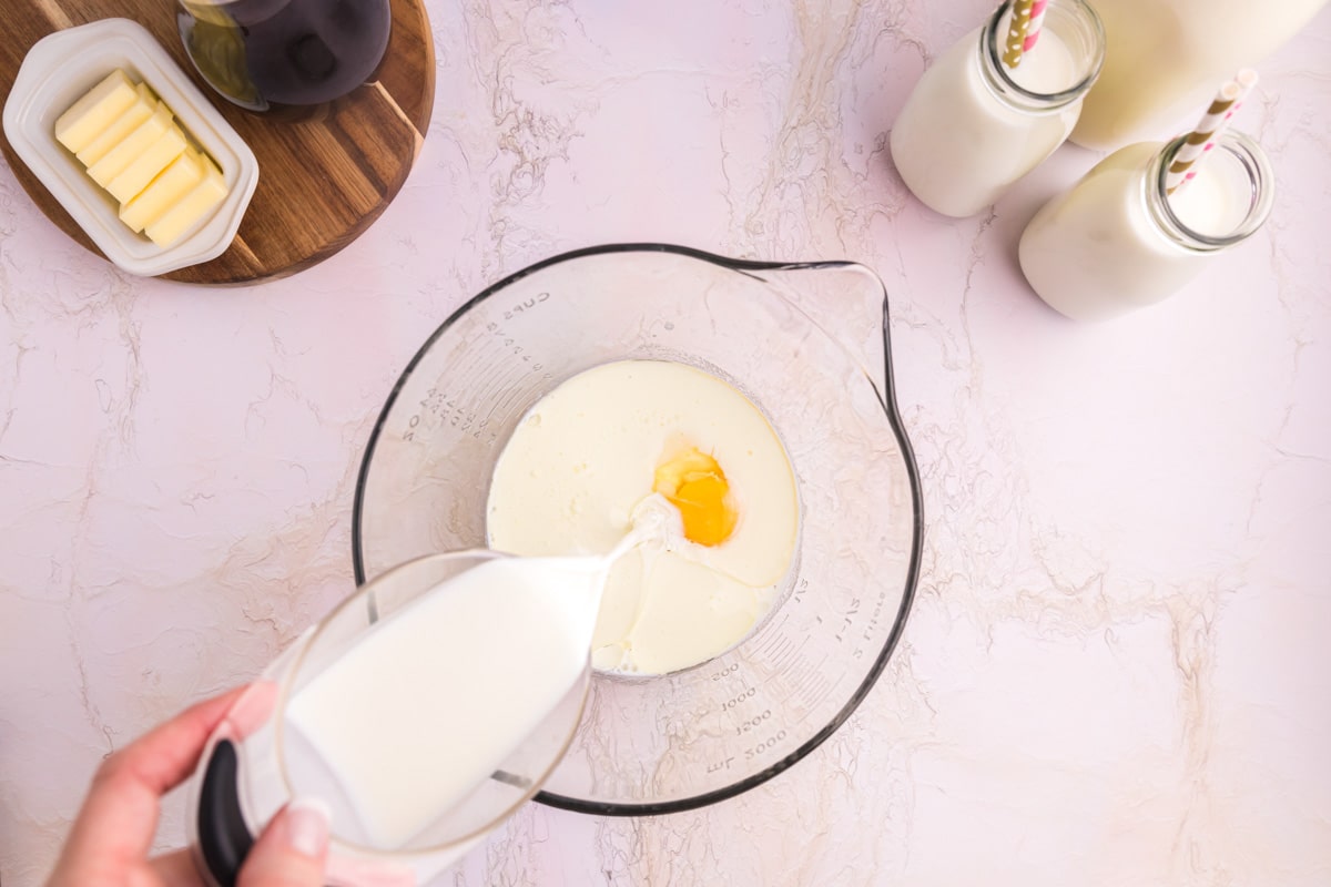 pouring milk in a glass bowl with an egg