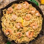 shrimp pasta in a skillet with parsley and lemon