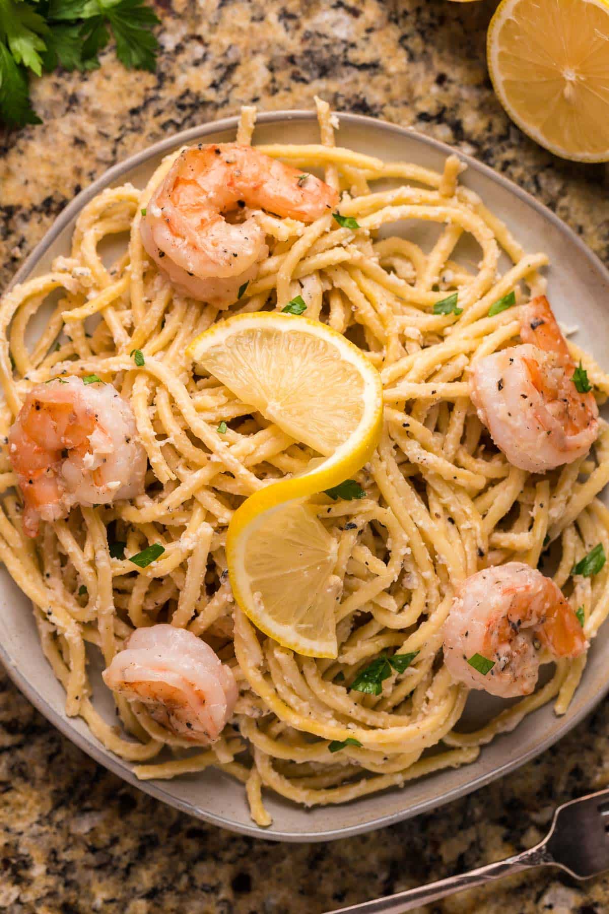 a plate of shrimp pasta garnished with a lemon
