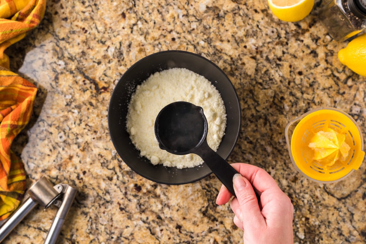 pouring pasta water over parmesan cheese in a bowl