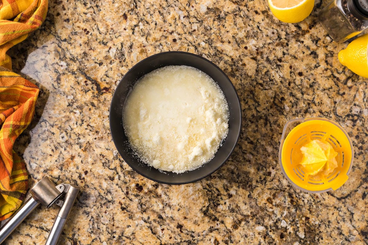 parmesan, pasta water and lemon juice in a bowl, unmixed