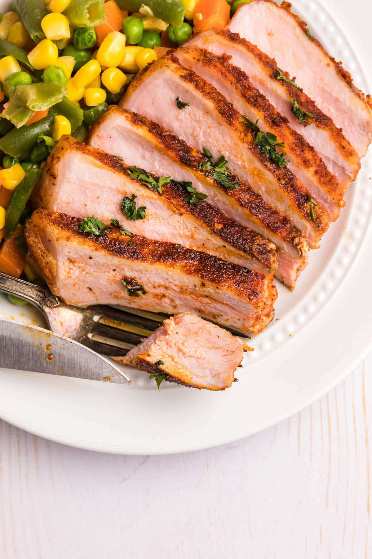 a sliced pork chop on a plate with veggies