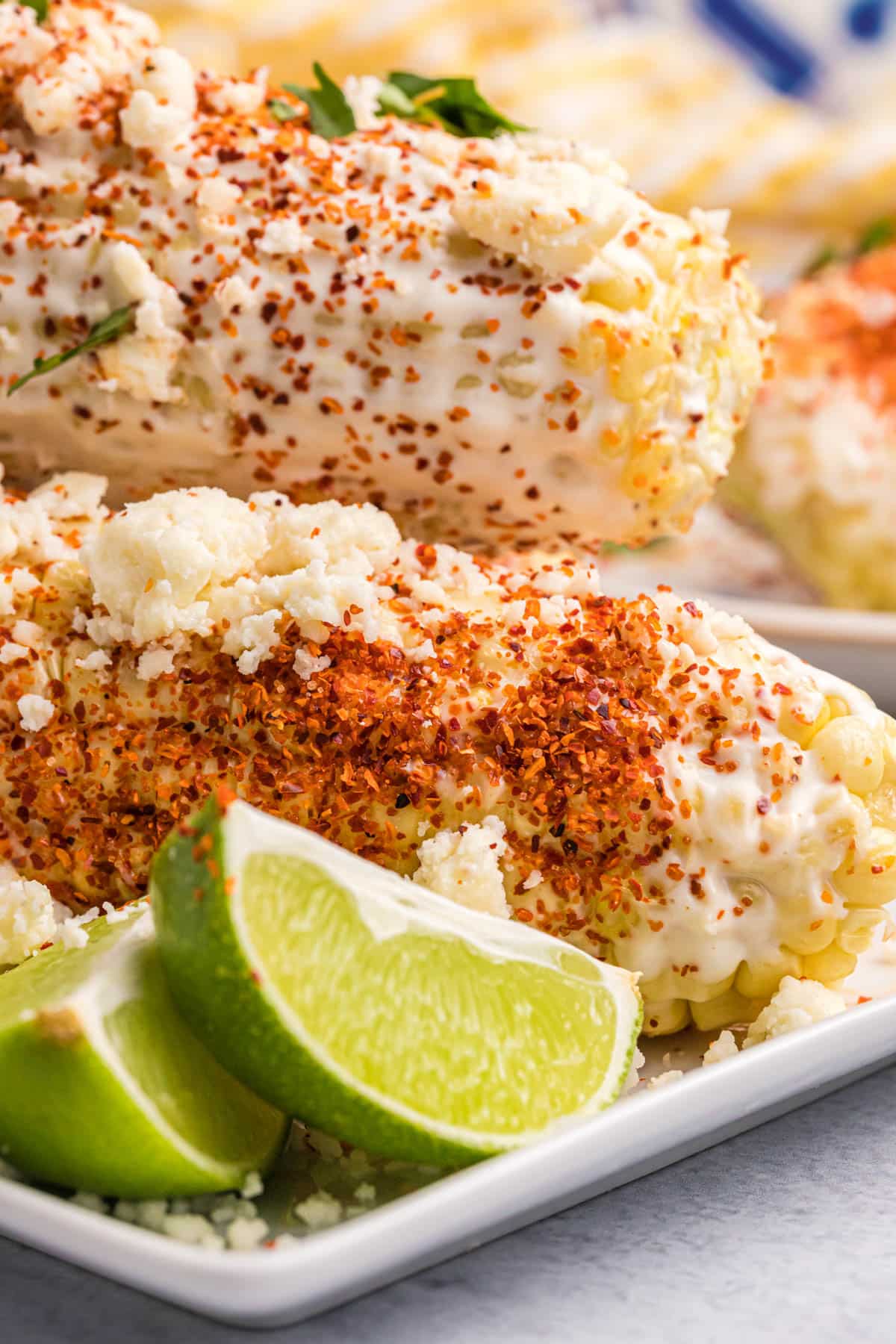 closeup of mexican street corn on a plate with limes