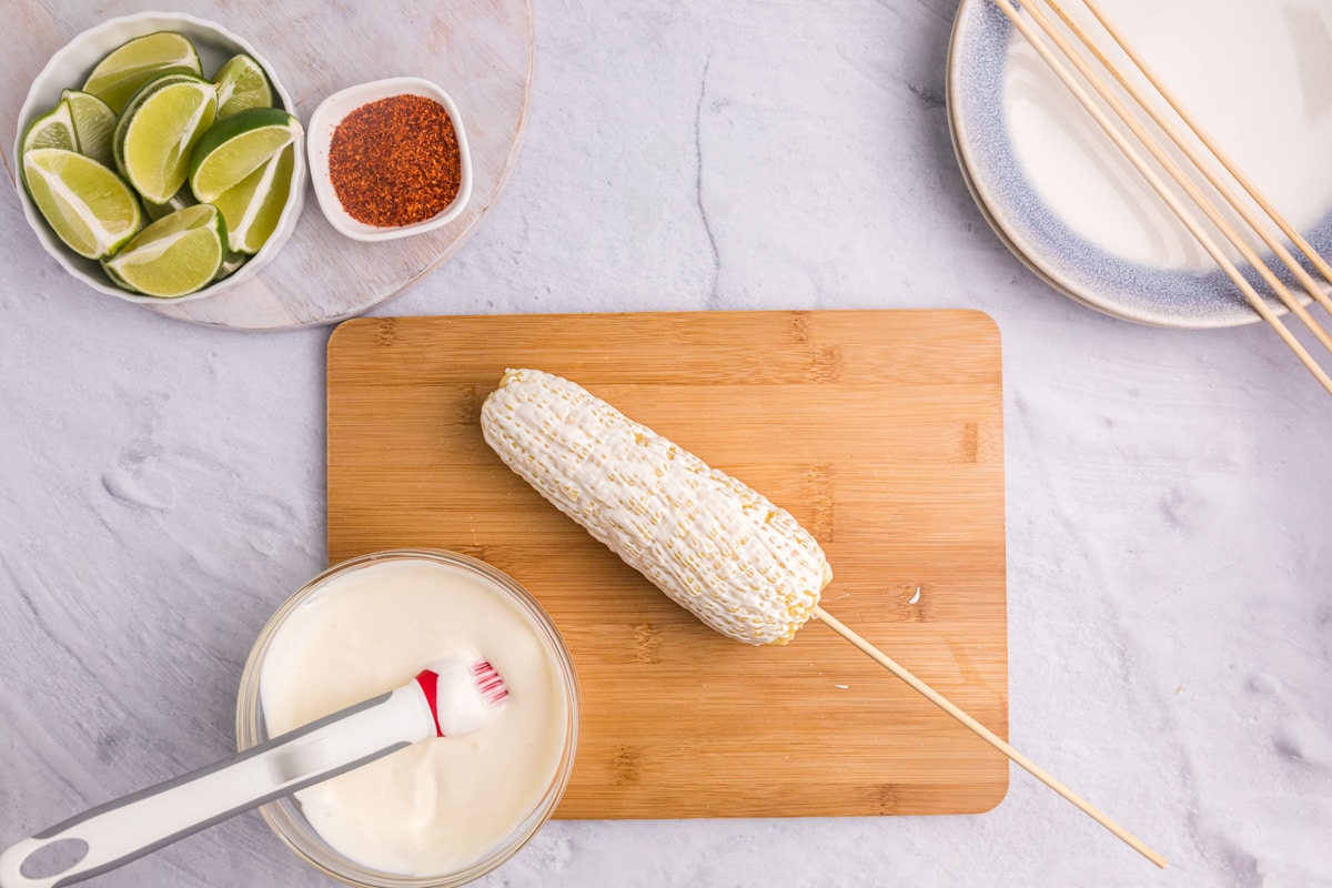 elote sauce brushed on an ear of corn