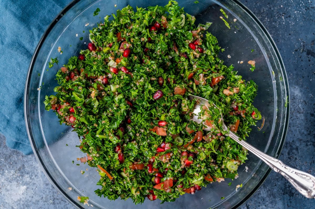 parsley salad mixed up in a glass bowl with a spoon
